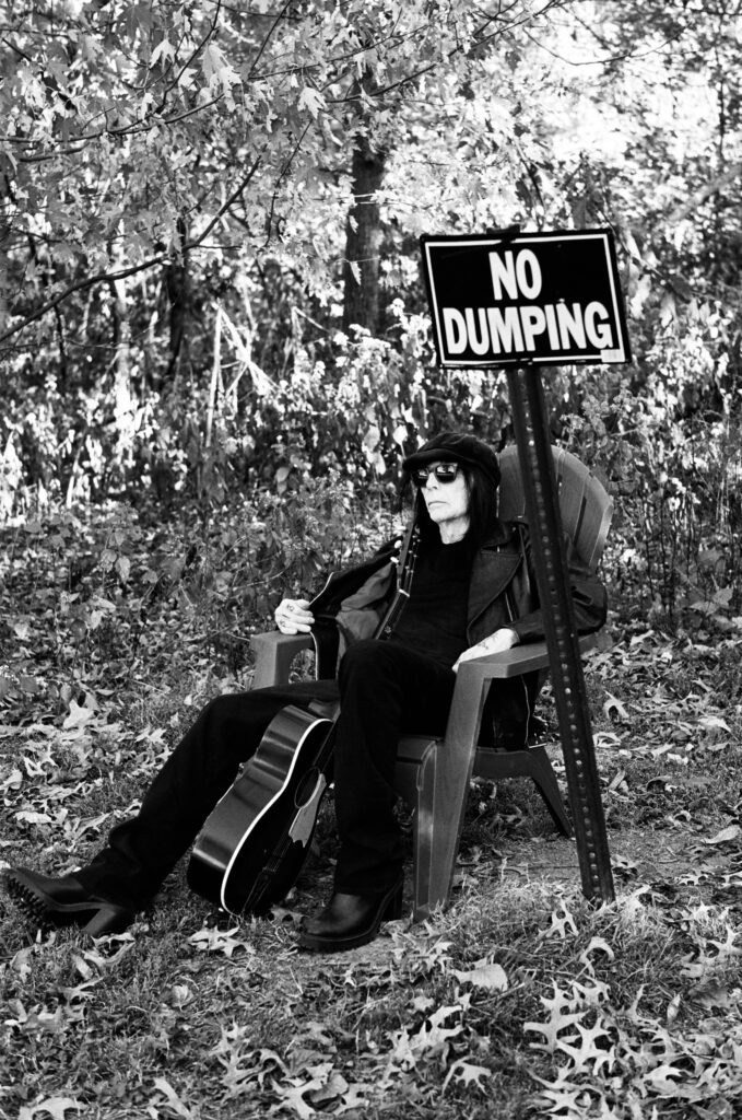 mick mars with guitar, sign reads no dumping
